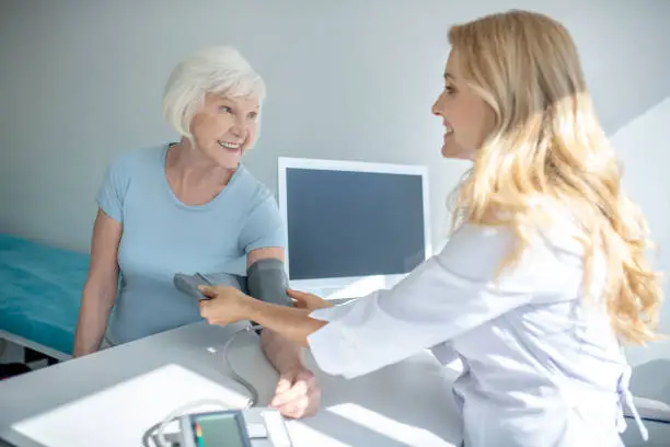 Blood-measure. Cardiologist measuring blood-pressure to good-looking elderly woman