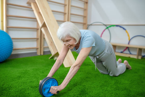 ältere frau trainiert in einem rehabilitationszentrum - kletterwand turngerät stock-fotos und bilder