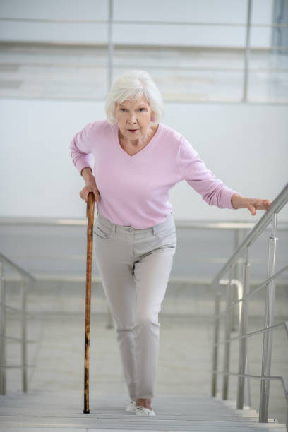 istock Elderly woman with a walking stick going upstairs 1280005264