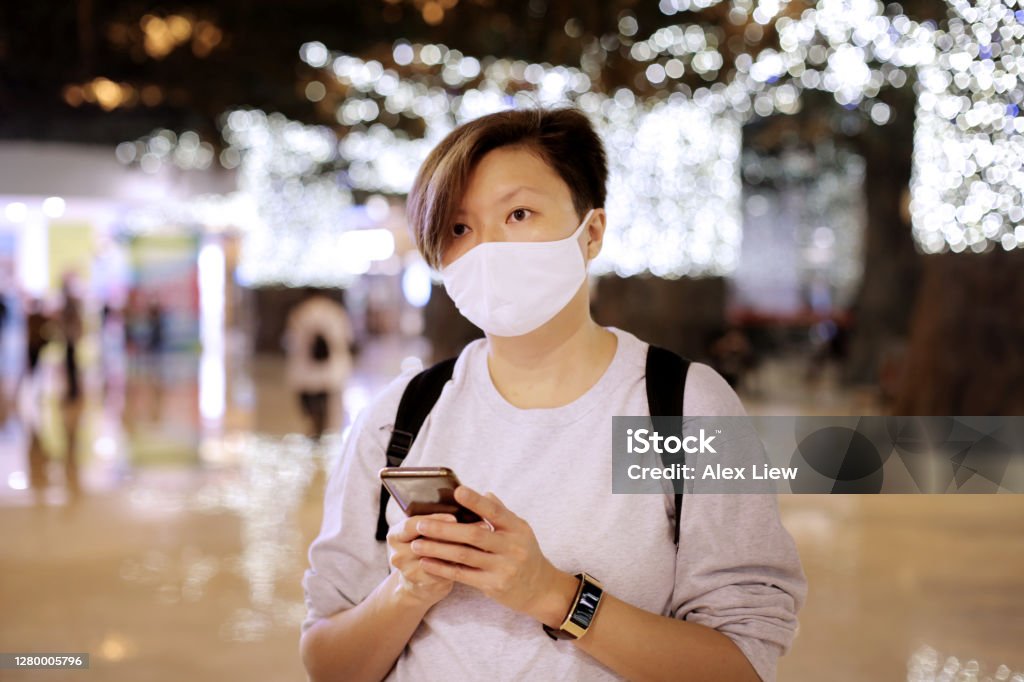 The New Norm A Chinese ethnicity female adult is using smartphone for online messaging. She is seen wearing face mask as part of the new norm in Malaysia. 35-39 Years Stock Photo