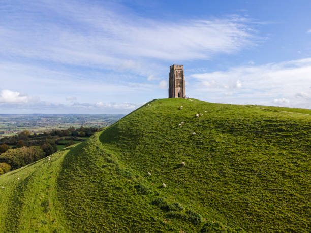 Despite the constantly changeable weather, wild flowers and cultivated blooms appear in a multitude of colours to brighten the dramatic landscape of the Somerset Levels and landmarks such as Glastonbury Tor on one of the  steep ridges of the outdoors countryside scenery during summer in Somerset, England, UK