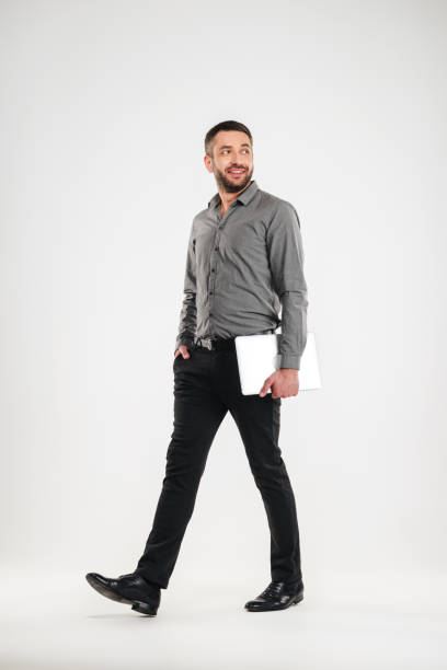 istock Cheerful man walking isolated holding laptop computer. 1280008552