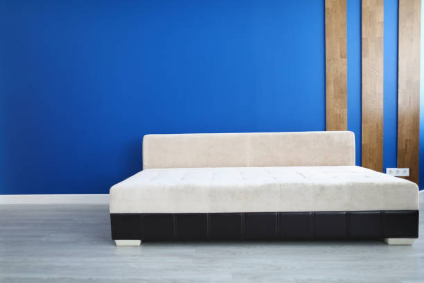 istock Stylish sofa stand on floor in room against blue wall. 1280009956