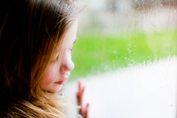 istock Sad little girl looking out the window 1280013801