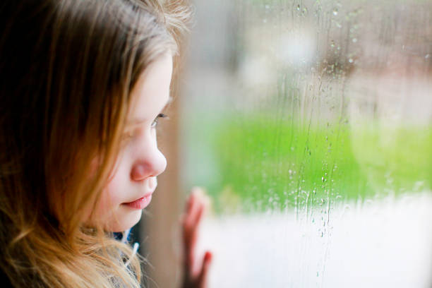 istock Sad little girl looking out the window 1280013808