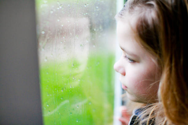 istock Sad little girl looking out the window 1280015788