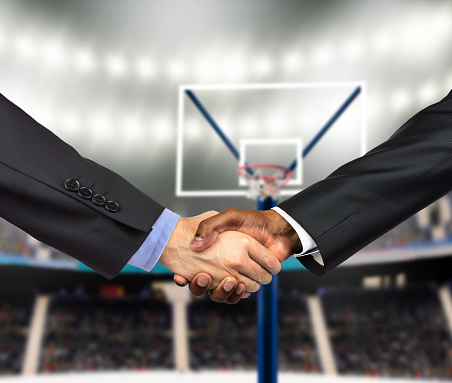 Cropped shot of two business people shaking hands together indoors on the basketball court