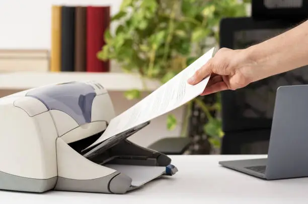 Man hand catching a document from a printer at home.