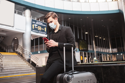 Using free wi-fi. A man wearing a face mask surfing internet via the smartphone