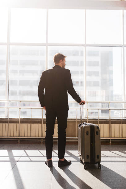 istock Man standing with a suitcase near the huge window 1280016891