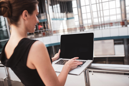 Urgent task. An elegant woman working with her computer in the airport
