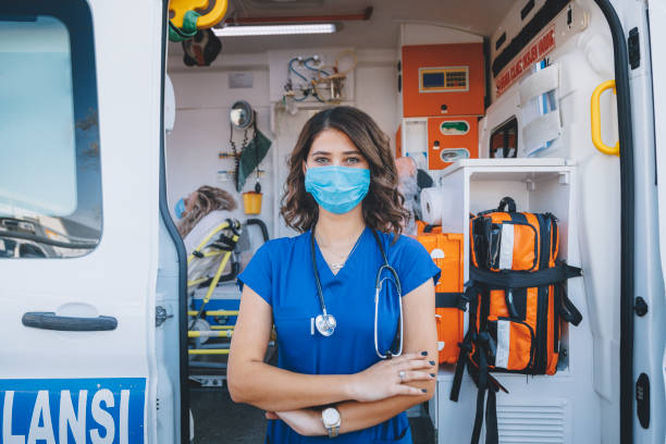 porträt einer jungen sanitäterin mit gesichtsmaske, die während einer pandemie in einem krankenwagen arbeitet - vehicle door flash stock-fotos und bilder