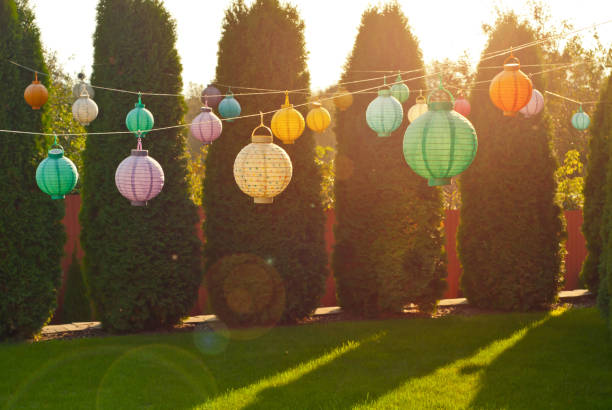 istock Paper lanterns hang on a string. Many lanterns on a background of green thuja. 1280018129