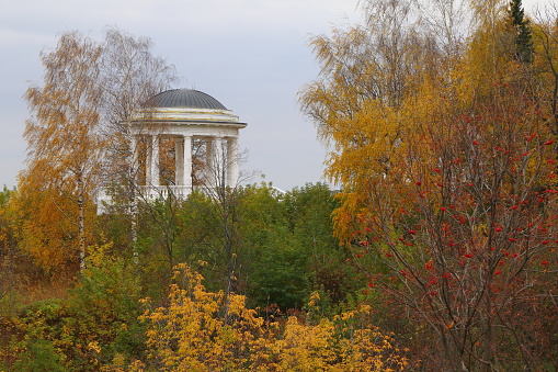 A white wooden rotunda in autumn park.