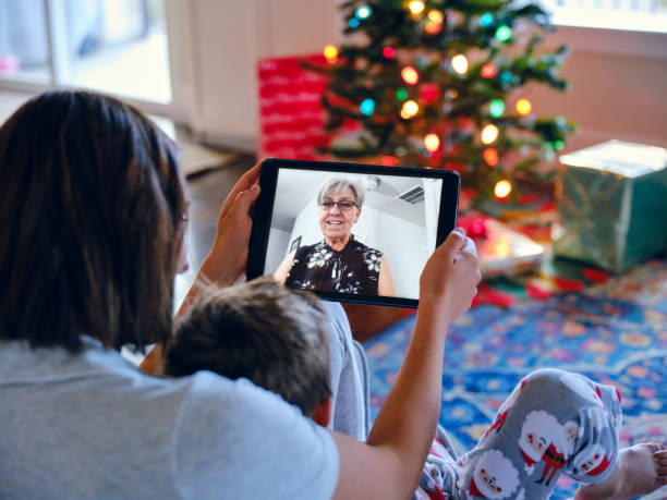 Webcam Chat with Grandma on Christmas Morning A young family chats with grandma over a webcam on Christmas morning. stay at home saying stock pictures, royalty-free photos & images