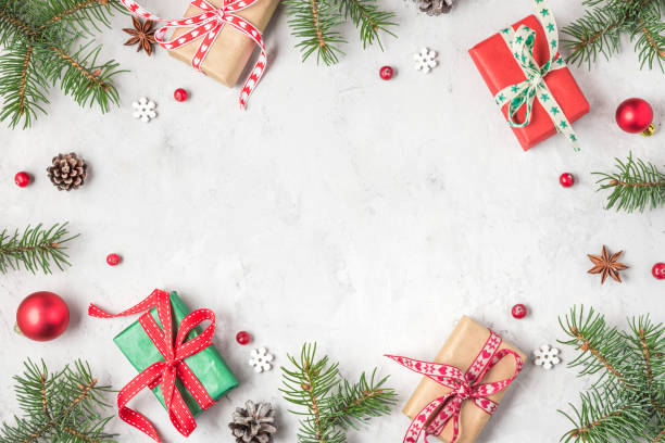 istock Christmas frame made of fir branches, red berries, gift boxes and pine cones on concrete table. Flat lay. top view 1280022216