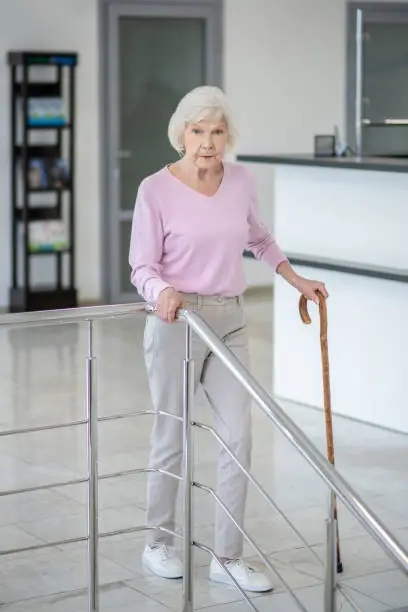 Elderly. Grey-haired womanwalking with a walking stick