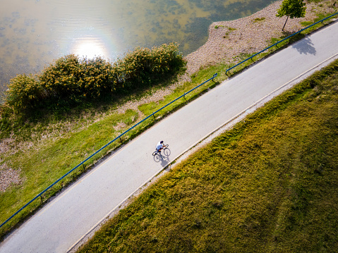 Mn riding bicycle by the lake outdoors to stay fit and healthy aerial top view. Cycling, sports and quality family time in the nature abstract