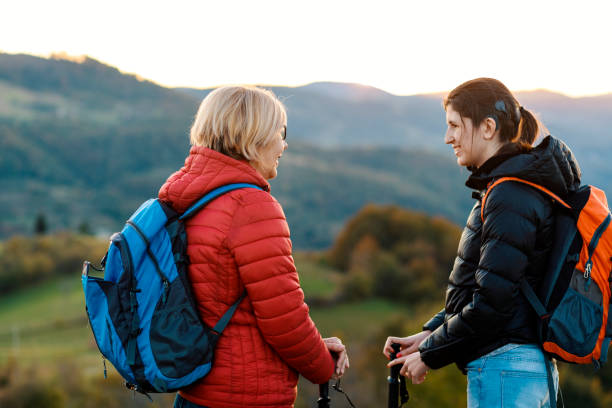 Happy backpackers hiking and exploring Happy mature woman enjoys hiking and adventure with her daughter in the stillness of a beautiful autumn day disabled person hiking outdoors stock pictures, royalty-free photos & images