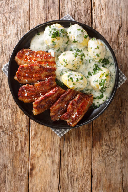 Stegt flæsk is a dish from Denmark consisting of fried pork belly and generally served with potatoes and a white sauce with parsley Vertical top view Stegt flæsk is a dish from Denmark consisting of fried pork belly and generally served with potatoes and a white sauce with chopped parsley Vertical top view from above danish culture stock pictures, royalty-free photos & images
