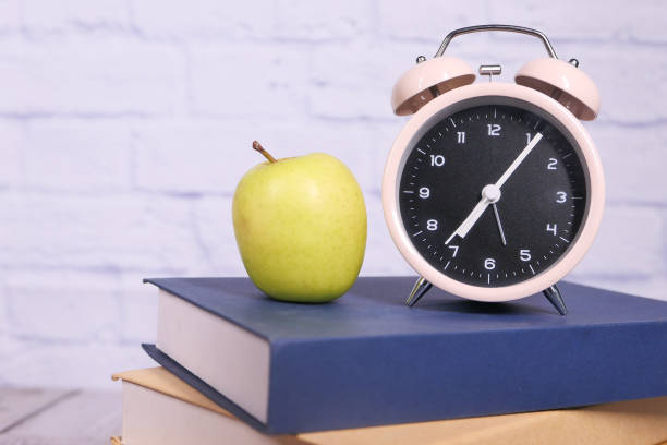 istock black to school concept with apple and clock on books on table. 1280025502