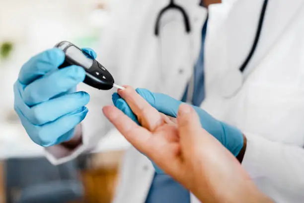 Geriatric male nurse measures the blood sugar level of a patient