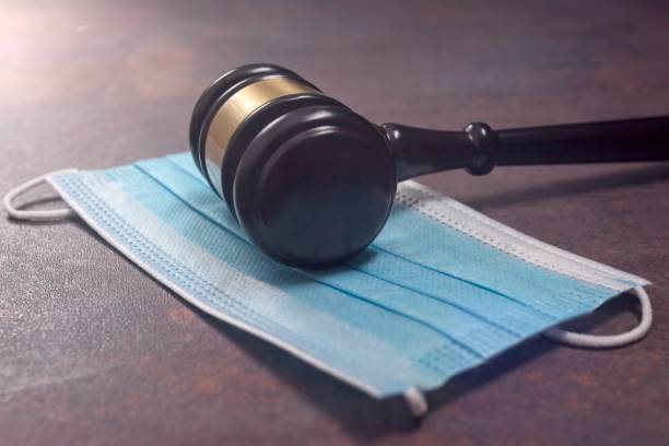 Close-up of a Judge Gavel Resting On A Protective Mask.
