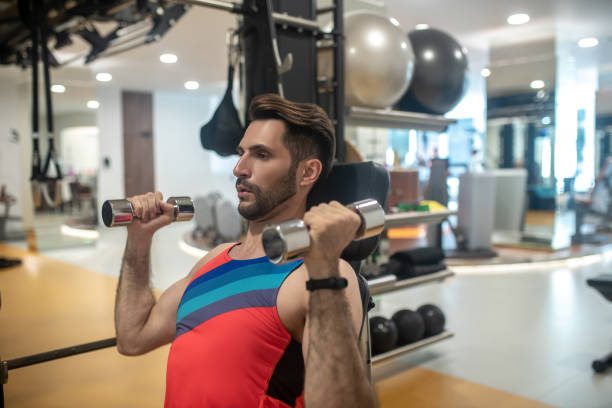 istock Young dark-haired man working on his arms on a gym machine 1280031497