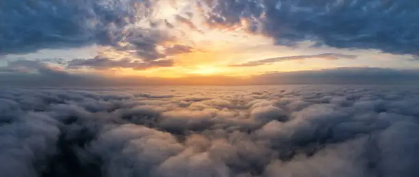 Photo of Beautiful dramatic sunset sky above fluffy clouds early in the morning. Drone view.