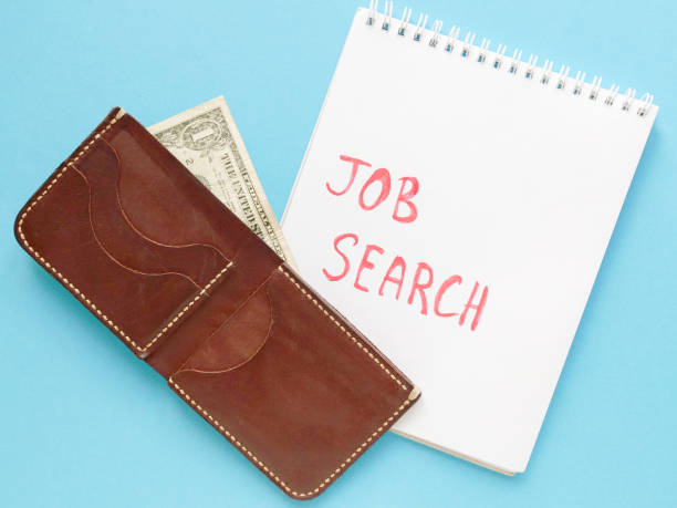 istock notebook with job search phrase, brown wallet, one dollar on blue background. looking for a work, last money, poverty, unemployment, job loss concept. Flat lay 1280034239