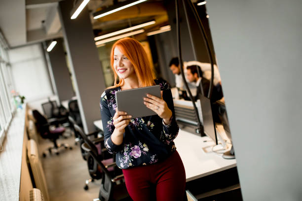 istock Young businesswoman working on digital tablet while in the background team working in the modern office 1280034263
