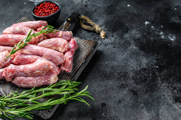 Raw chicken neck meat on a cutting board. Black background. Top view. Copy space