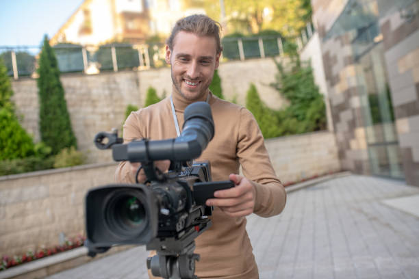 istock Fair-haired cameraman standing behind camera, getting ready for filming 1280043492