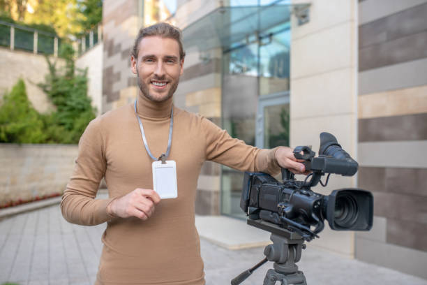 istock Smiling operator standing near camera in front of modern building 1280043494