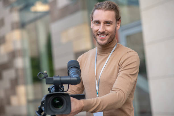 istock Smiling fair-haired cameraman standing behind camera, posing 1280043502