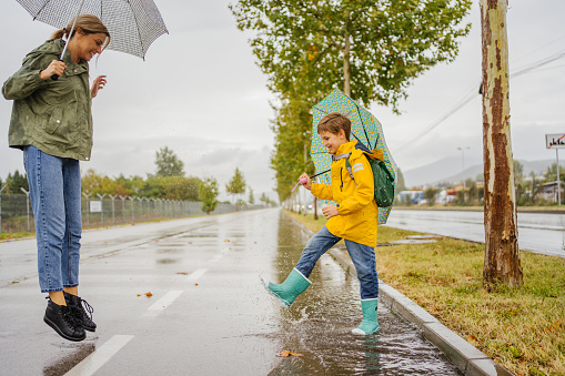 Photo of a young woman and her son having fun outdoors on a rainy day.