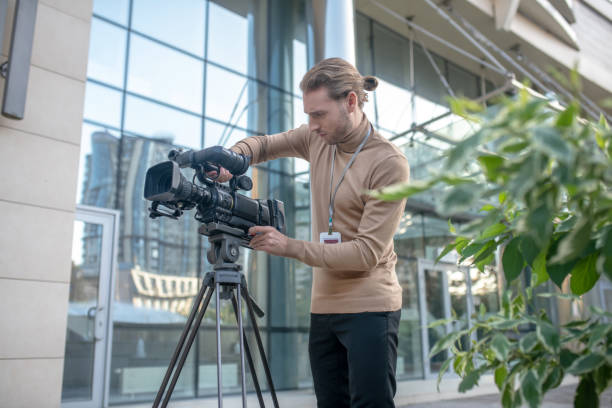 istock Involved operator fixing camera to tripod in front of modern building 1280044165