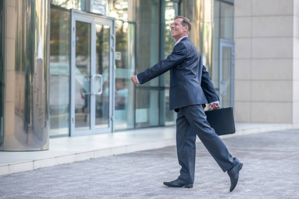 istock Smiling mature businessman going inside business center 1280044270