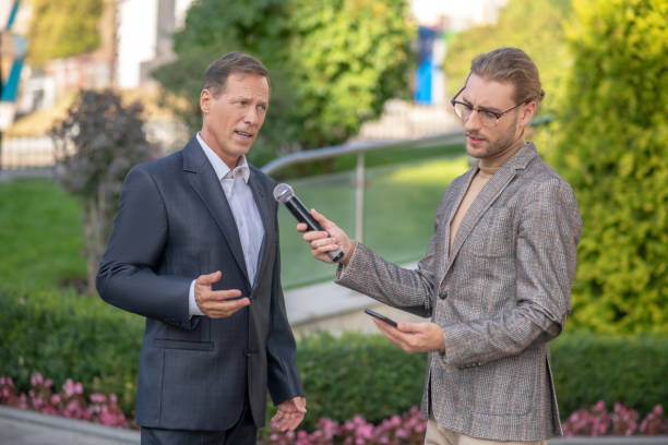 istock Male journalist taking taking inteview with mature man, recording it 1280044309