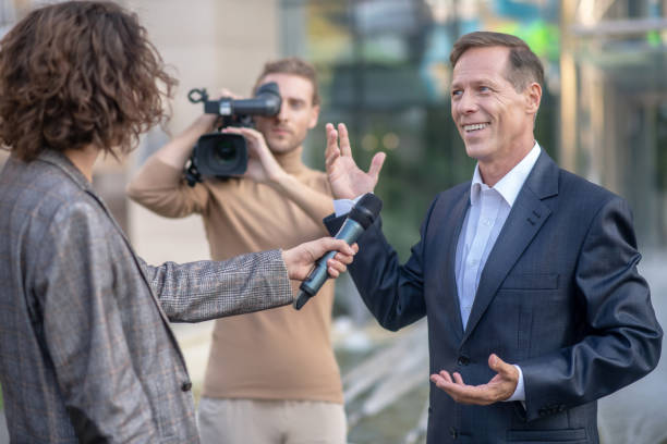 istock Long-haired operator filming curly female journalist interviewing smiling businessman 1280044385