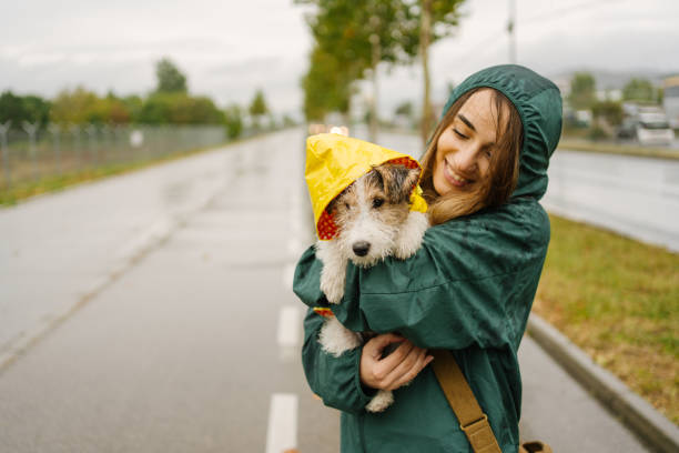 Walking my dog on a rainy day Photo of a young woman and her puppy having fun outdoors on a rainy day. raincoat stock pictures, royalty-free photos & images