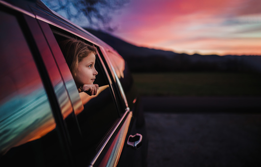 Little girl looking out her car window in awe of all the colors