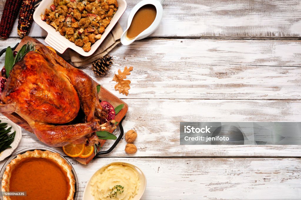 Traditional Thanksgiving turkey dinner. Top view side border on a rustic white wood background. Traditional Thanksgiving turkey dinner. Top view side border on a rustic white wood background with copy space. Turkey, stuffing, mashed potatoes and pumpkin pie. Thanksgiving - Holiday Stock Photo