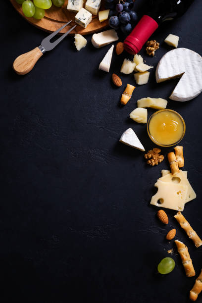cornice menù con diversi tipi di formaggio, miele, uva e vino su sfondo nero - cheese antipasto cracker grape foto e immagini stock