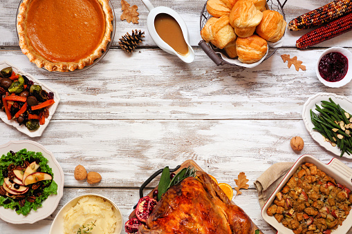 Classic Thanksgiving turkey dinner. Top down view frame on a rustic white wood background with copy space. Turkey, mashed potatoes, dressing, pumpkin pie and sides.