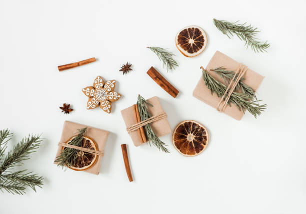 istock Christmas flat lay composition of craft gift boxes on the white background. Hand made brown paper box with Christmas tree branch and cinnamon sticks and dry orange. 1280048622