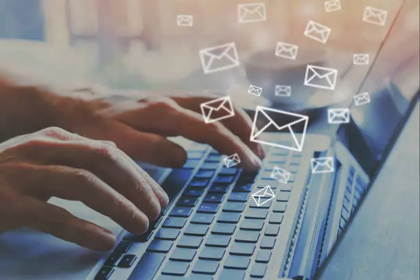 email marketing concept, e-mail icons, hands typing on keyboard as background