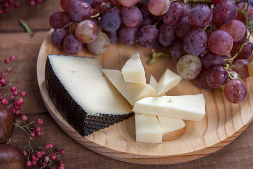 Top view of cheese plate with grapes on wooden table