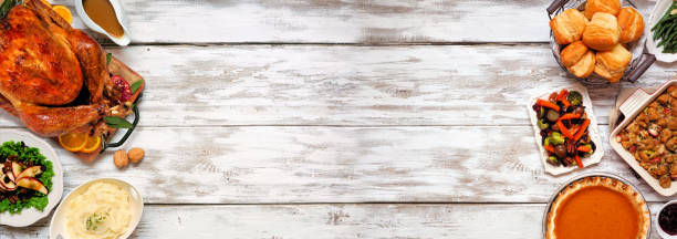 istock Traditional Thanksgiving turkey dinner. Overhead view double border on a rustic white wood banner background. 1280054299