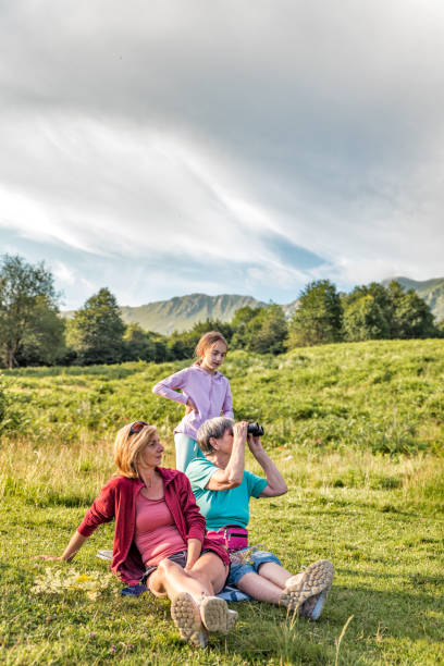 istock Cheerful Women of Three Generation Family Relaxing and Exploring the View Using Binocular on Mountain Meadow on Sunny Summer Day 1280057231